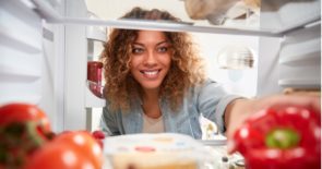 Woman grabbing a red pepper from the refrigerator.
