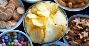 Closeup of bowls of potato chips, crackers, cookies and candies.