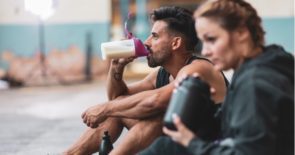 Athletic man and woman sitting drinking protein shakes