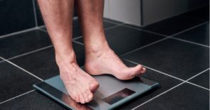 Close-up of bare feet standing on a bathroom scale.